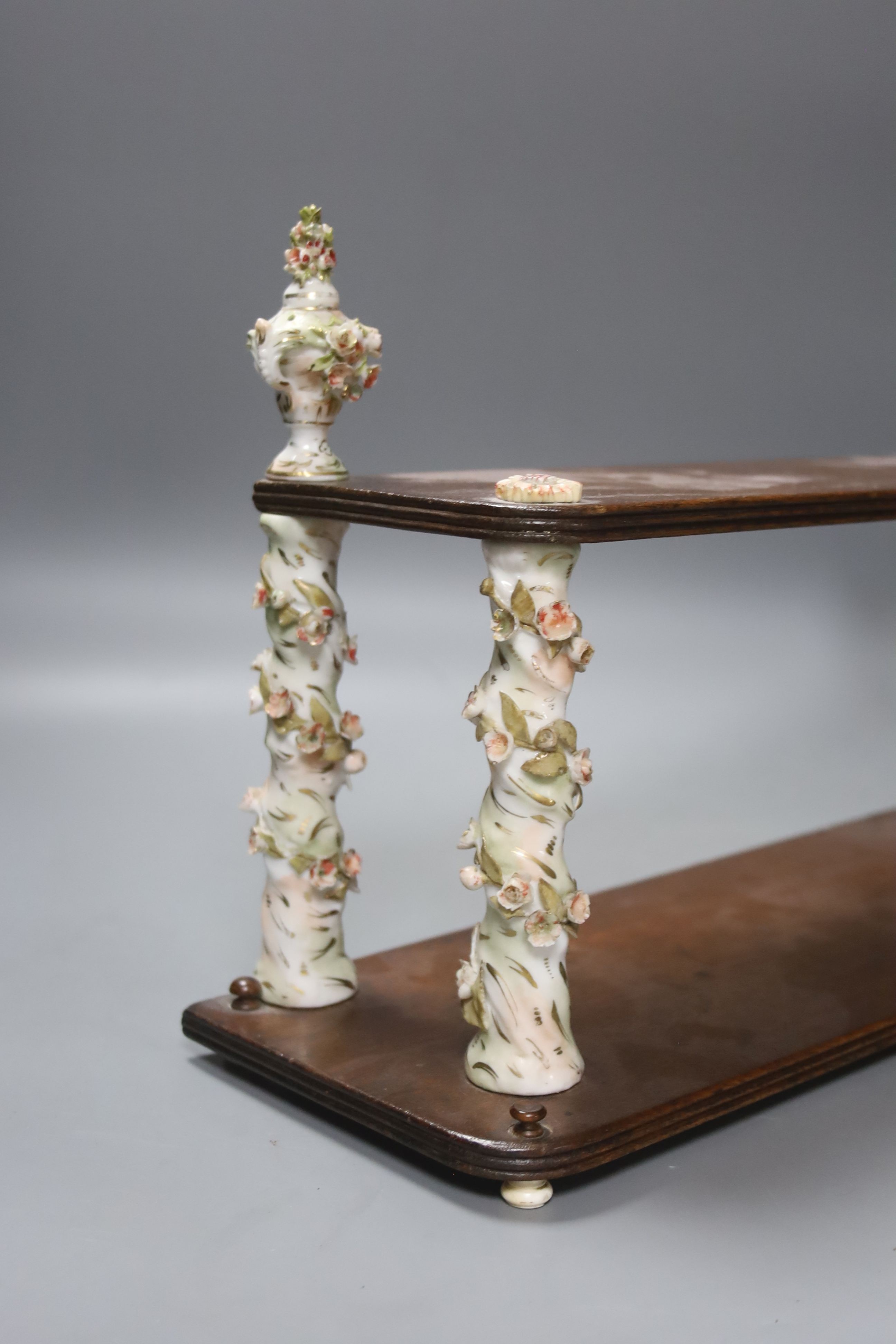 A Continental mahogany and floral encrusted porcelain two tier wall shelf